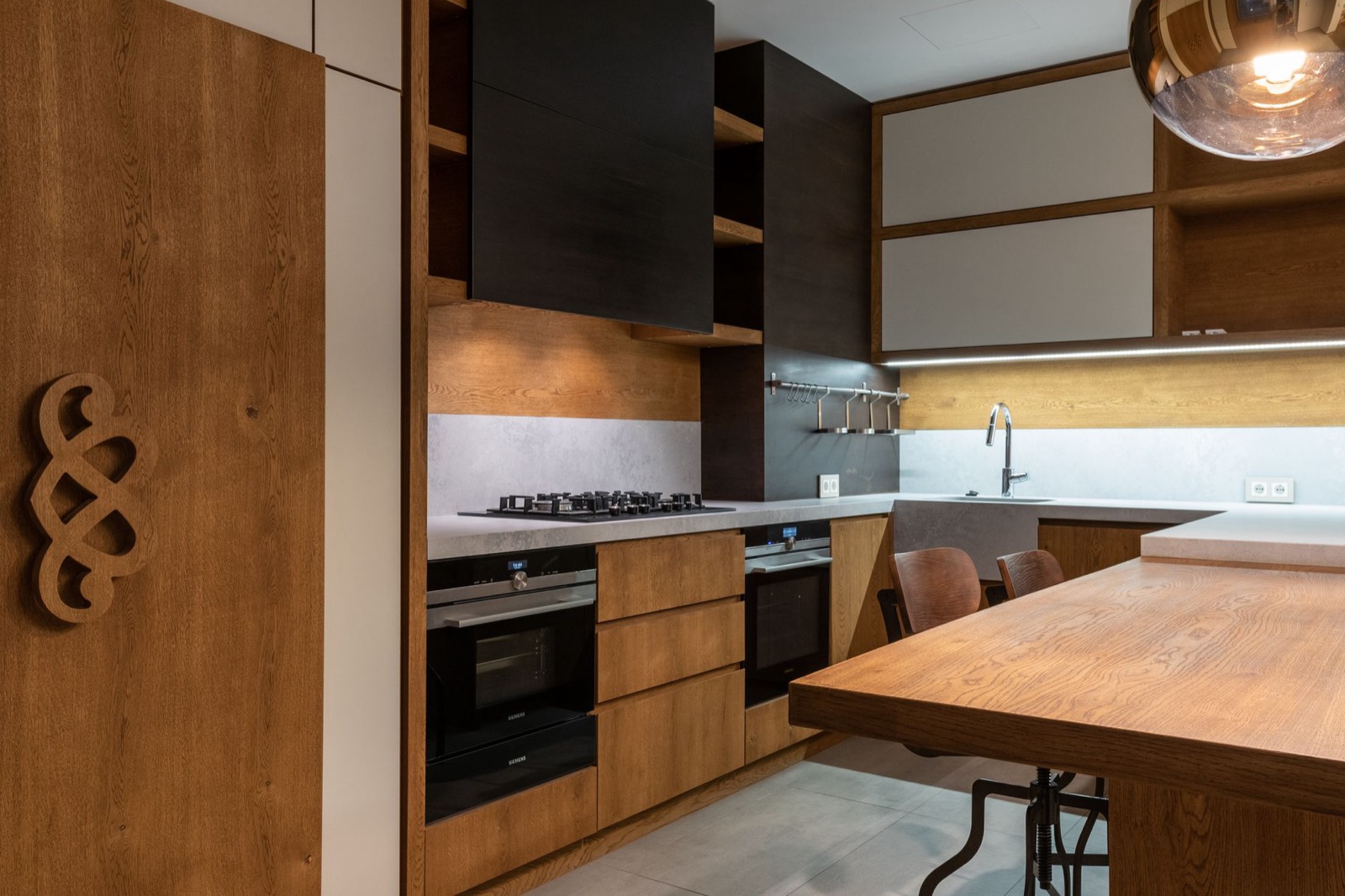 A modern kitchen with wood cabinetry, a full stove, and a dining table, representing a real furnished kitchen setup
