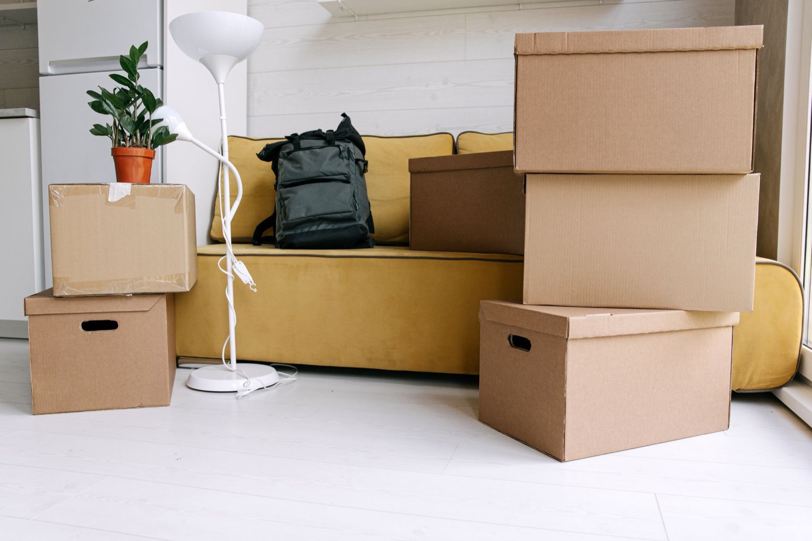 Moving boxes and a backpack stacked in a bright living room, packed for a move