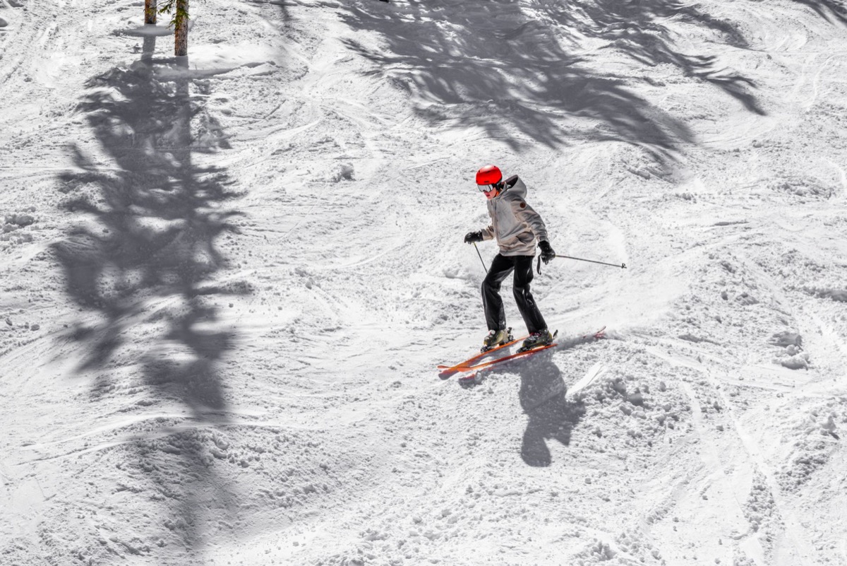 Skier in a red helmet carving down a sunlit snowy run, similar to the terrain at Sunrise Park Resort near Pinetop